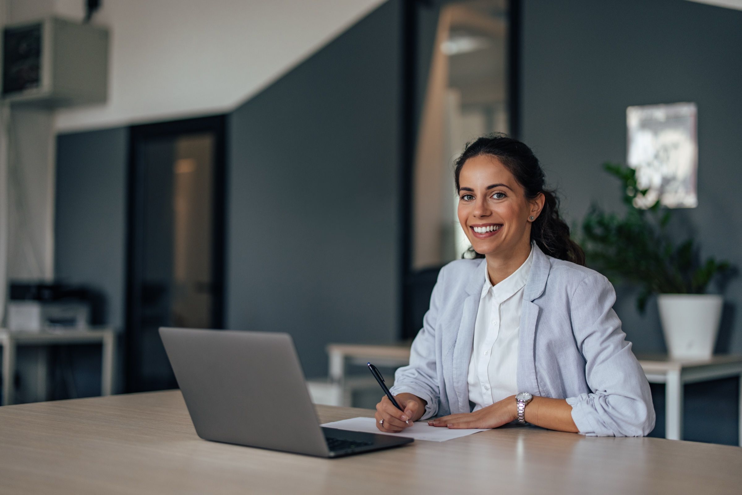Contadora sonriendo en su escritorio, con la laptop abierta.