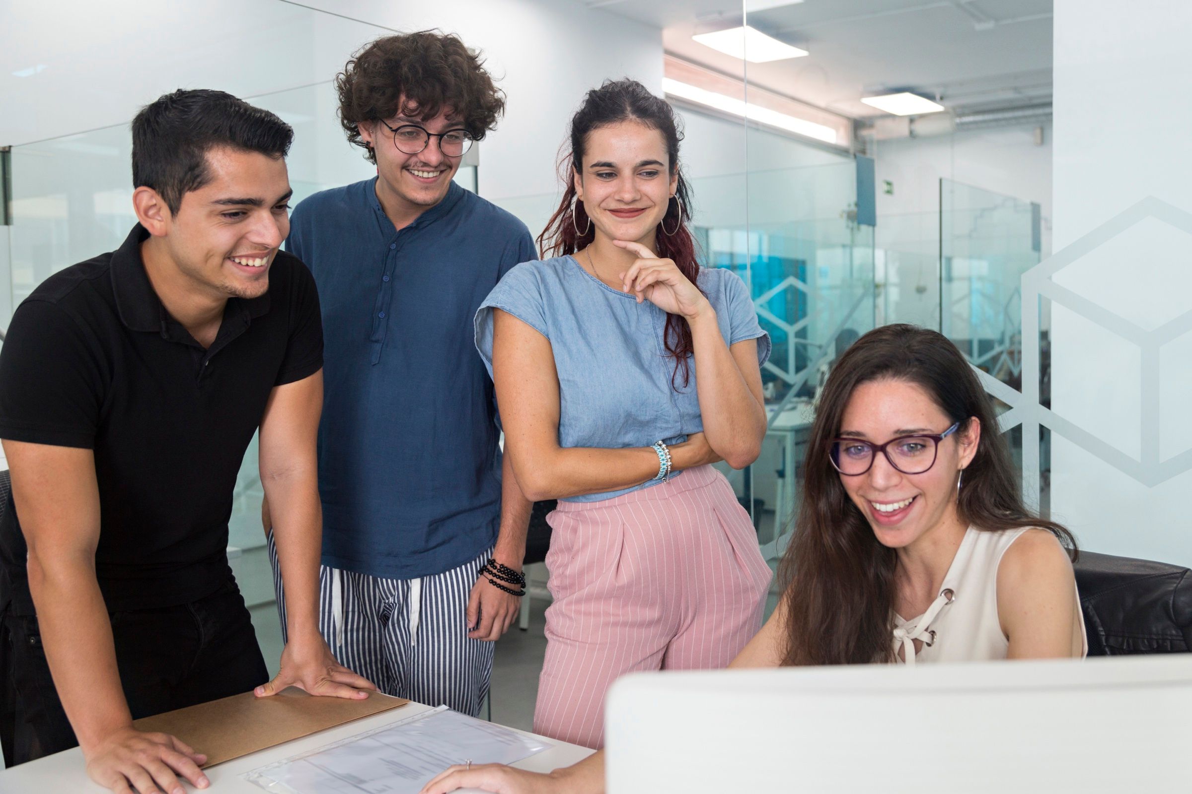Equipo de un despacho, sonriendo frente a la pantalla de una compañera.